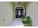 Inviting entrance featuring a decorative glass front door and lush greenery, creating a warm welcome at 10093 Holly Berry Dr, Weeki Wachee, FL 34613