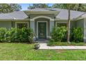 Inviting front entrance with decorative glass door, manicured shrubs, and vibrant green lawn at 10149 Rockbay Rd, Brooksville, FL 34601