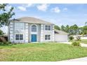 Charming two-story home with a blue front door, attached garage, and lush green lawn at 10386 Norvell Rd, Spring Hill, FL 34608