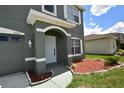 Close-up view of a two-story home's arched entryway, manicured lawn with shrubbery, and siding at 15160 Durango Cir, Brooksville, FL 34604