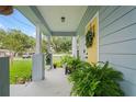 Charming covered front porch with a yellow door, lovely green plants and seating at 1601 E 98Th Ave, Tampa, FL 33612