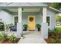 Inviting front porch featuring a bright yellow door, modern planters, and cozy seating at 1601 E 98Th Ave, Tampa, FL 33612