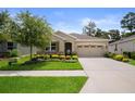 Well maintained home with a lush green lawn, beautiful flowerbeds, and a two-car garage at 17727 Garsalaso Cir, Brooksville, FL 34604