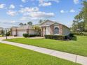 Charming single-story home with a well-manicured lawn, brick accents, three-car garage and a brick paver driveway at 18845 Fairway Green Dr, Hudson, FL 34667