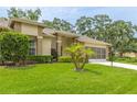 Charming single-story home featuring a well-maintained lawn, mature trees, and a screened garage at 2481 Whispering Pines Ct, Spring Hill, FL 34606