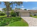 Well-maintained home exterior with brick driveway, mature tree, and a two-car garage at 2486 Deer Trail Ln, Spring Hill, FL 34606