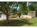 Exterior view of a cozy yellow house with lush landscaping and mature trees at 3140 Bahia Ave, Holiday, FL 34690