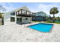 Backyard view of pool and home with black railinged deck, and a paved patio area at 4104 Pine Dale Ct, Hernando Beach, FL 34607