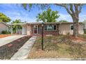 Charming single-story home with a brick facade, mature trees, and a well-maintained front yard and covered carport at 4537 Cynthia Ln, Spring Hill, FL 34606