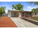 View of a tan home, showcasing the charming brick facade, carport, well-manicured garden bed, and tidy driveway at 4537 Cynthia Ln, Spring Hill, FL 34606