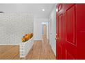 Inviting foyer with a striking red door, white brick accent wall, and wood-look flooring at 507 Jewel St, Brooksville, FL 34601
