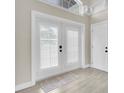 Bright entryway featuring double doors with white shutters, complemented by light gray walls and tile flooring at 5440 Manatee Point Drive, New Port Richey, FL 34652
