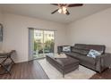 Living room with wood floors, ceiling fan, leather sofa, and access to the balcony at 5520 White Marlin Ct, New Port Richey, FL 34652