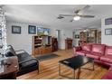 Cozy living room with hardwood floors, ceiling fan, and an electric fireplace at 7608 Dale Dr, Port Richey, FL 34668
