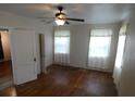 Bright bedroom with hardwood floors, ceiling fan, and natural light from two windows at 1042 Howell Ave, Brooksville, FL 34601