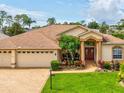 Inviting single-story home with a brick driveway, lush landscaping, and a welcoming double-door entrance at 11144 Brambleleaf Way, Hudson, FL 34667