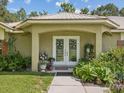Inviting front porch with decorative double doors, complemented by lush greenery and charming decor at 12229 Barnevelde Rd, Weeki Wachee, FL 34614
