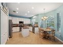 Bright kitchen with white cabinets, stainless steel appliances, a center island, and an adjacent dining area at 1410 Halapa Way, Trinity, FL 34655