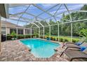 Beautiful screened-in pool with brick surround, lounge chairs, and lush greenery in the backyard at 1410 Halapa Way, Trinity, FL 34655