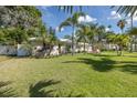 Lush front yard with palm trees, a charming single-story home, and inviting outdoor seating create a serene setting at 1830 Santa Barbara Dr, Dunedin, FL 34698