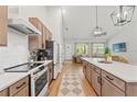 Modern kitchen with stainless steel appliances, island with quartz countertop, and hardwood flooring at 27295 Tarbel Rd, Brooksville, FL 34602