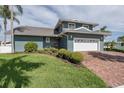 Charming two-story waterfront home features a brick driveway, lush lawn, and manicured landscaping at 3150 Trident Ter, New Port Richey, FL 34652