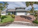 Charming two-story waterfront home features a brick driveway, lush lawn, and mature palm trees at 3150 Trident Ter, New Port Richey, FL 34652