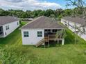 Back exterior showcasing a wooden deck with stairs leading to the grassy backyard at 4082 Watson Dr, New Port Richey, FL 34655