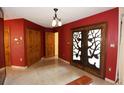 Foyer showcasing unique tree-themed double doors, neutral tile flooring, and red accent wall at 4269 River Birch Dr, Spring Hill, FL 34607