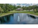 Scenic aerial shot of a tranquil pond with a fountain and a home in the background at 7275 Crystal Spring Run, Weeki Wachee, FL 34607