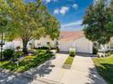 A front view showing the villas with a well-kept lawn, mature landscaping and attached garages at 7518 Mediterranean Ct, Hudson, FL 34667