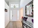 Bright foyer with wood floors, high ceilings, transom window, and stylish mirror at 7518 Mediterranean Ct, Hudson, FL 34667