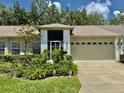 Charming single Gathering home showcasing lush landscaping and an attached two-car garage with a brick-paved driveway at 18142 Baywood Forest Dr, Hudson, FL 34667