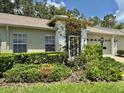 Landscaped front yard with mature trees and white brick home at 18142 Baywood Forest Dr, Hudson, FL 34667