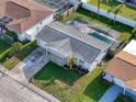 Aerial view of a home with gray roof, screened-in pool, and a long driveway leading to the attached garage at 10029 Freestone Ln, Port Richey, FL 34668