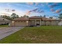 Charming single-story home featuring a well-manicured lawn and an attached two-car garage at dusk at 12026 Penguin Ave, Weeki Wachee, FL 34614