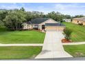 Attractive single-story home boasts a lush green lawn, tidy landscaping, and three car garage at 12060 Sapphire Dr, Spring Hill, FL 34609