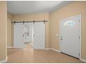Bright foyer with tile flooring, barn doors to the kitchen, and a white front door at 13049 Moonstone Way, Spring Hill, FL 34609