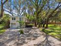 Charming two-story home featuring a light beige exterior, complemented by landscaped yard, wooden deck and lush trees at 13901 Vacation Ln, Odessa, FL 33556