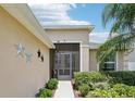 Close-up of the screened front door showing tasteful decorations, lush landscaping, and decorative metal stars at 18530 Dobson Dr, Hudson, FL 34667