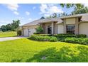 Charming home featuring a manicured lawn, complemented by lush landscaping and a two car garage at 18736 Bent Pine Dr, Hudson, FL 34667