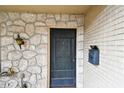 Close-up of the front door featuring stone accents and a vintage mailbox at 2101 Sunset Point Rd # 201, Clearwater, FL 33765
