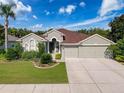Charming single-Gathering home with a well-manicured front lawn and a three-car garage at 2326 Mountain Ash Way, New Port Richey, FL 34655