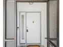 Close up of a white front door framed by glass panels and the security of a screen door at 2404 Knoll Dr, Spring Hill, FL 34608