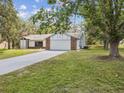 Beautiful front exterior showcasing the home's brick and white siding, spacious driveway and lush, green front yard at 2404 Knoll Dr, Spring Hill, FL 34608
