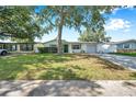 A cozy single-Gathering home boasts a lush green lawn and mature trees at 3118 Lloyd Dr, Holiday, FL 34691
