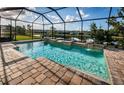 A screened-in pool area featuring a water feature and brick pavers, with views of the serene backyard pond at 4197 Glade Wood Loop, New Port Richey, FL 34655