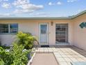 The front door and walkway with tiled landing are flanked by tropical vegetation at 4567 Great Lakes S Dr, Clearwater, FL 33762