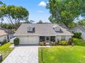 Well-manicured home with dormer windows and a spacious driveway leads up to a convenient two-car garage at 6282 Darien Way, Spring Hill, FL 34606