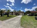 Single-story home featuring an attached garage, long driveway, and a well-maintained lawn at 8312 Split Rail Ln, Hudson, FL 34667